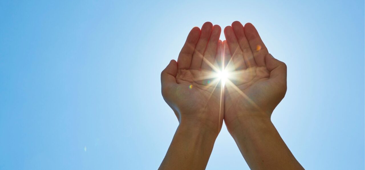 太陽に手を掲げる